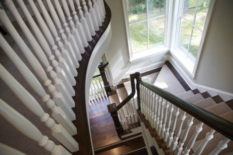 Beautiful interior curved staircase with dark wood and white spindles